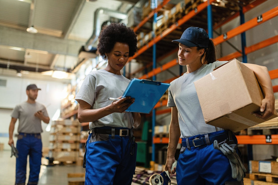 Two warehouse employees checking inventory logs in a distribution facility, illustrating supply chain continuity and operational efficiency for bulk buyers.